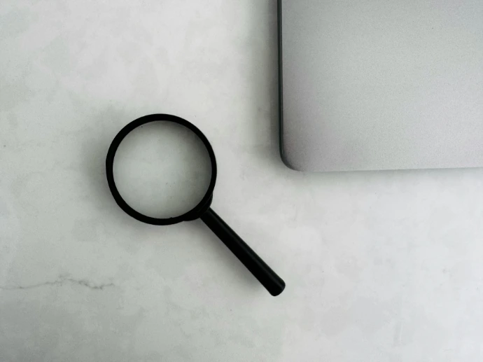 Magnifying glass sits near a laptop on a table.